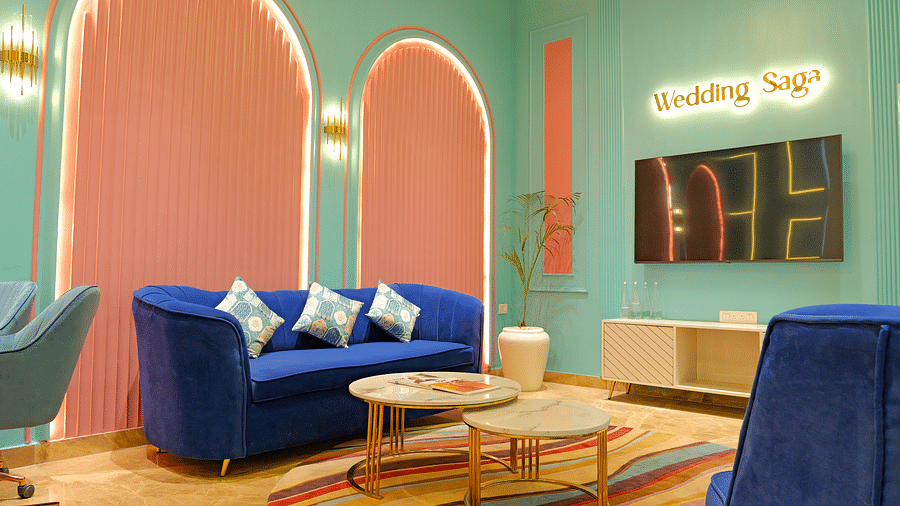 A brightly lit wedding saga  at The Gaurs Sarovar Premiere, with blue seating, a coffee table, and abstract wall decorations.