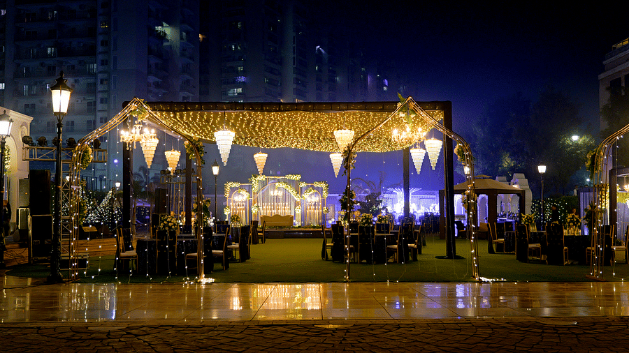 An outdoor event setup at The Gaurs Sarovar Premiere at night, with illuminated decorations and a covered stage area.