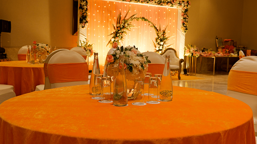 A decorated stage at The Gaurs Sarovar Premiere, with a round table and chairs, suggesting a setup for a wedding reception or similar event