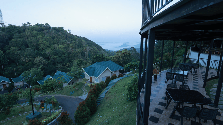 The outdoor dining area overlooking the several villas with turquoise rooftops scattered downhill at Aveda Mountains and Mist Resort and Spa, Munnar.