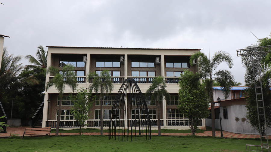 Exterior architectural view of a multi-storey resort wing with large glass windows and manicured front lawn - DAN Resorts & Weddings, Palghar