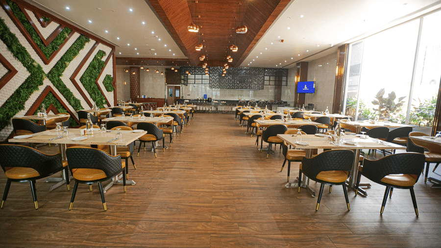 A spacious restaurant interior with contemporary furniture, wooden floors, and a decorative green wall - Leroy Grand, Yeshwanthpur