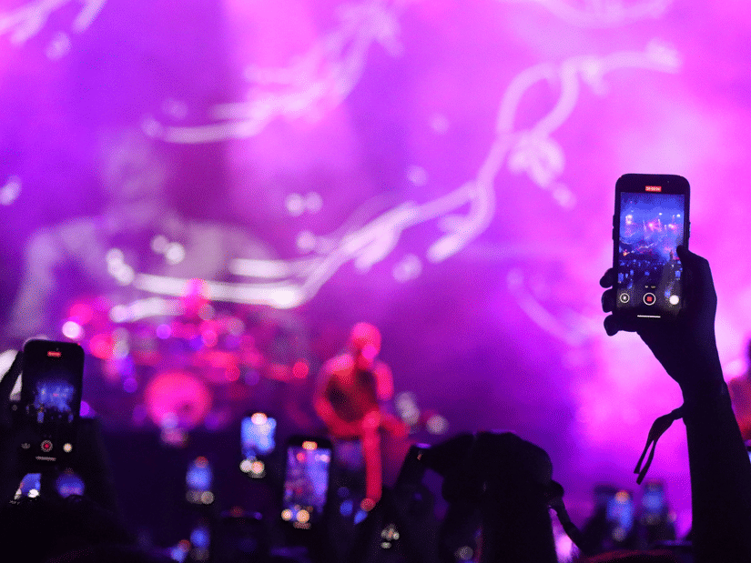 Crowd recording a live music performance with colourful stage lighting