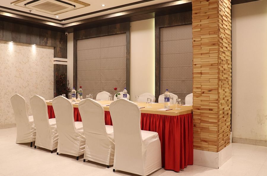 A large table with chairs on both sides, illuminated by bright lighting at Hotel Uday Palace.