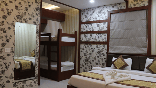 A spacious room at Hotel Uday Palace featuring a large mirror to the side and a neatly made bed.