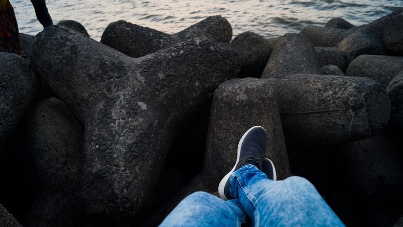 A person sitting in Marine Drive in Mumbai with rocks near the waterbody