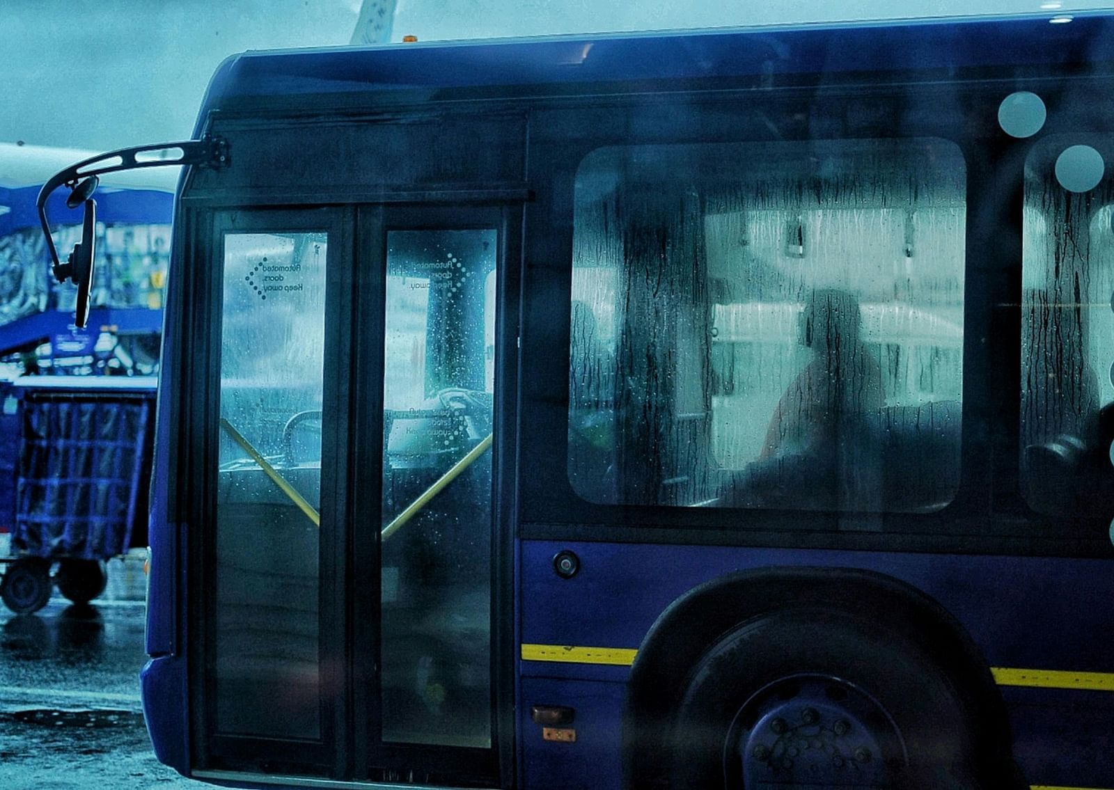 An Indigo bus carrying people to the plane in an airport on a rainy day