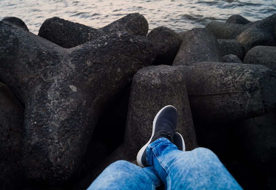 a person sitting with their legs dangling over tetrapods
