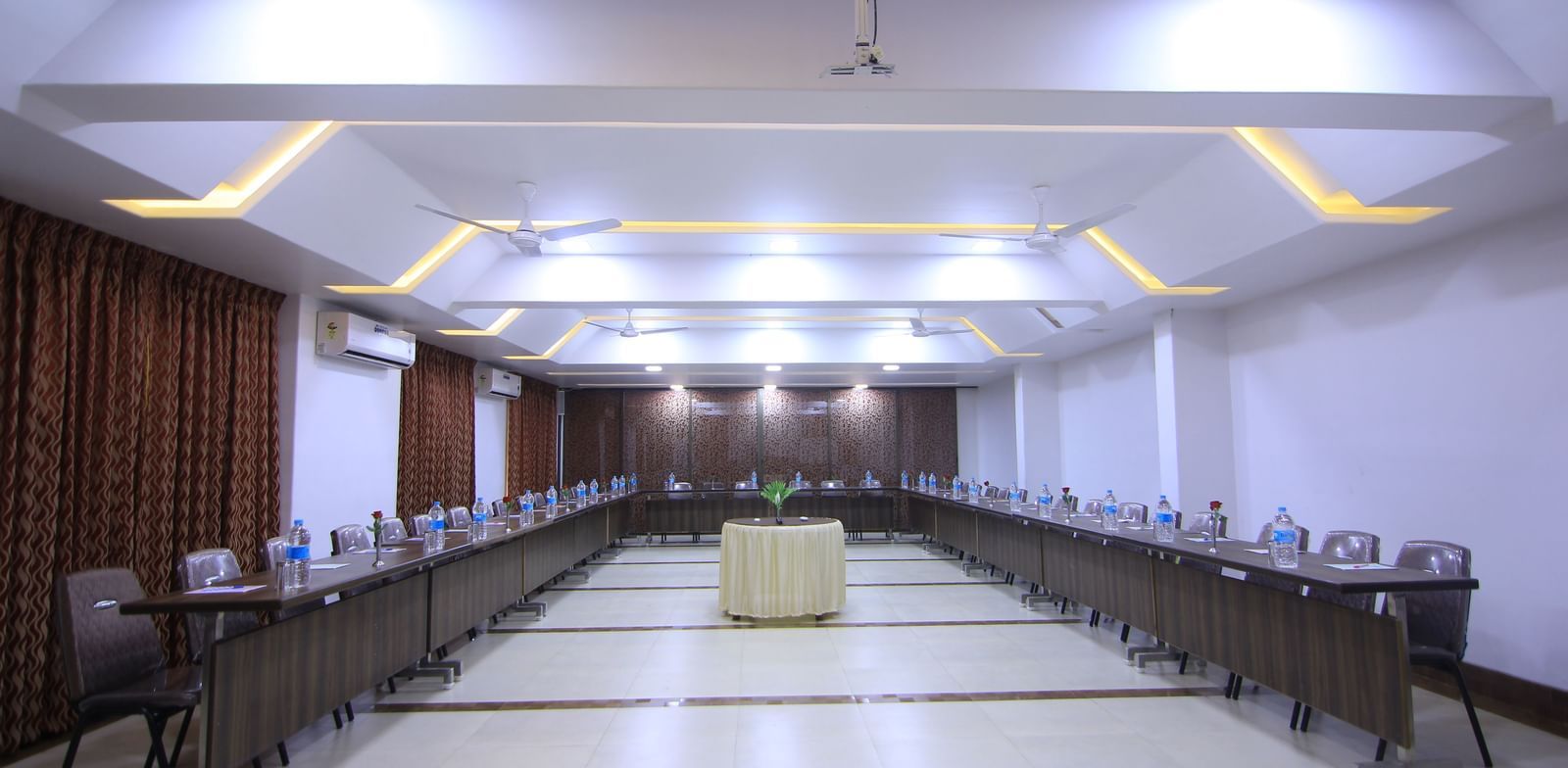 A well-lit conference room at Krushnai Resort with tables set up in a U-shaped arrangement.