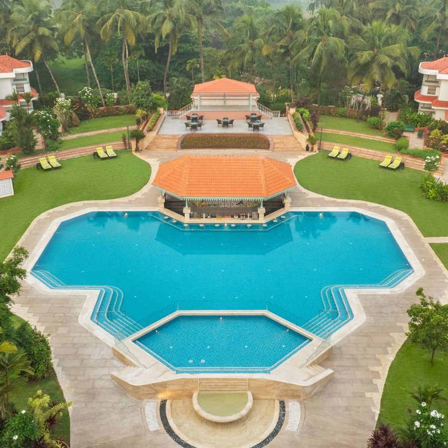 Aerial view of a large resort with a central swimming pool and landscaped gardens.