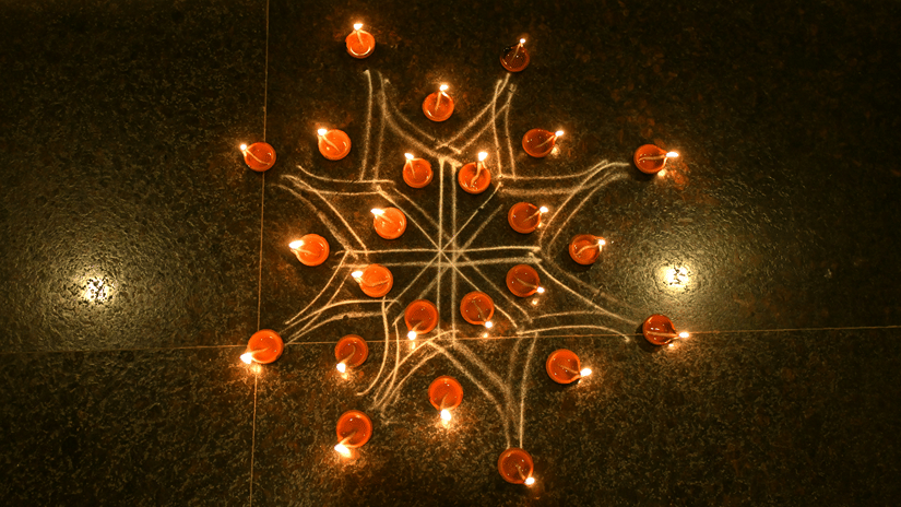 Traditional oil lamps for Karthigai Deepam in Tamil Nadu arranged in a star-shaped pattern, glowing against a dark background