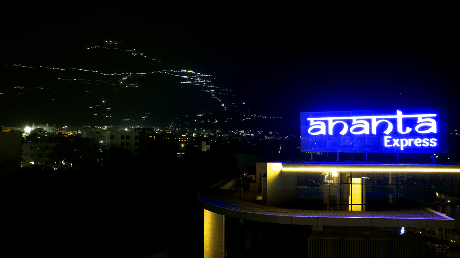 The Ananta Express rooftop sign illuminated in blue light against a dark night sky at Ananta Express, Katra.
