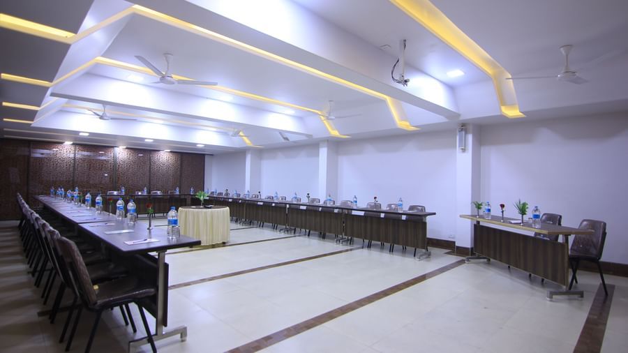 A meeting room with a U-shaped table arrangement, empty chairs, and a small podium at the centre at Krushnai Resort.