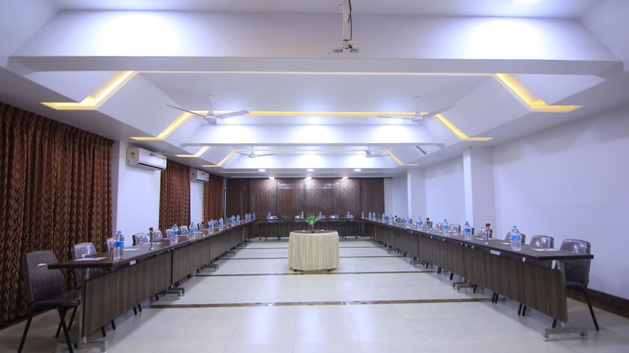 A well-lit conference room at Krushnai Resort with tables set up in a U-shaped arrangement.