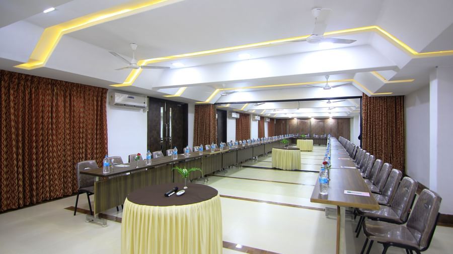 Wide view of a conference room at Krushnai Resort showing tables arranged in a U-shape with chairs on both sides, multiple round tables placed evenly at the centre.