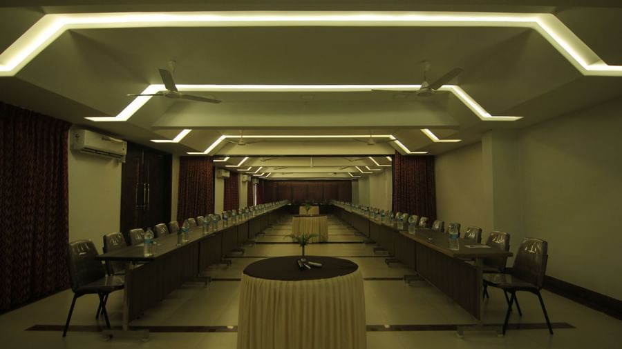 A dim-lit event space with tables arranged in a neat layout at Krushnai Resort.
