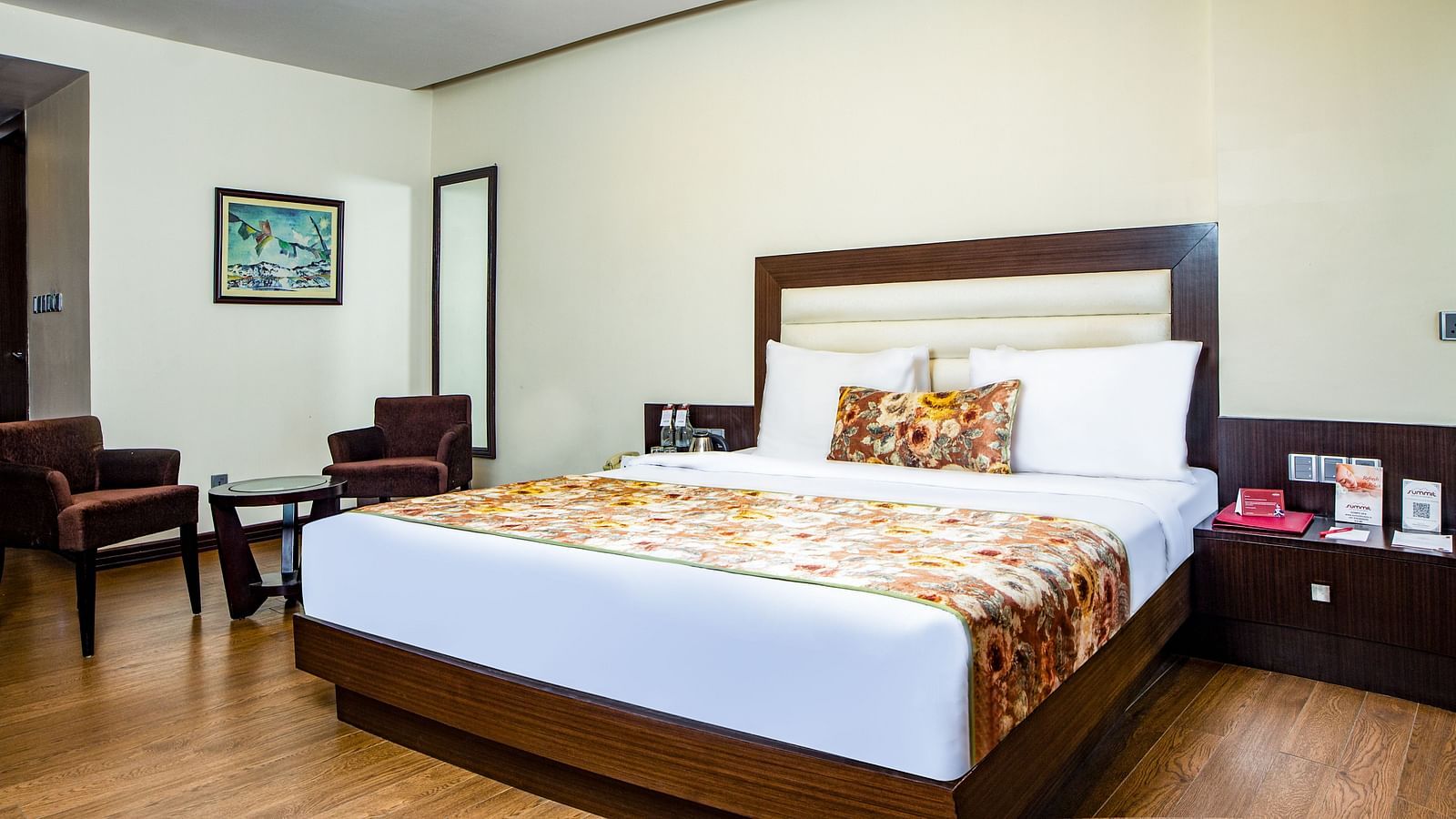  Junior Suite featuring a spacious and neatly made bed, with two bedside tables holding essentials arranged aesthetically. The suite also includes two comfortable sofas, a glass table in the centre, and a full-length mirror on the wall, at Summit Montana S