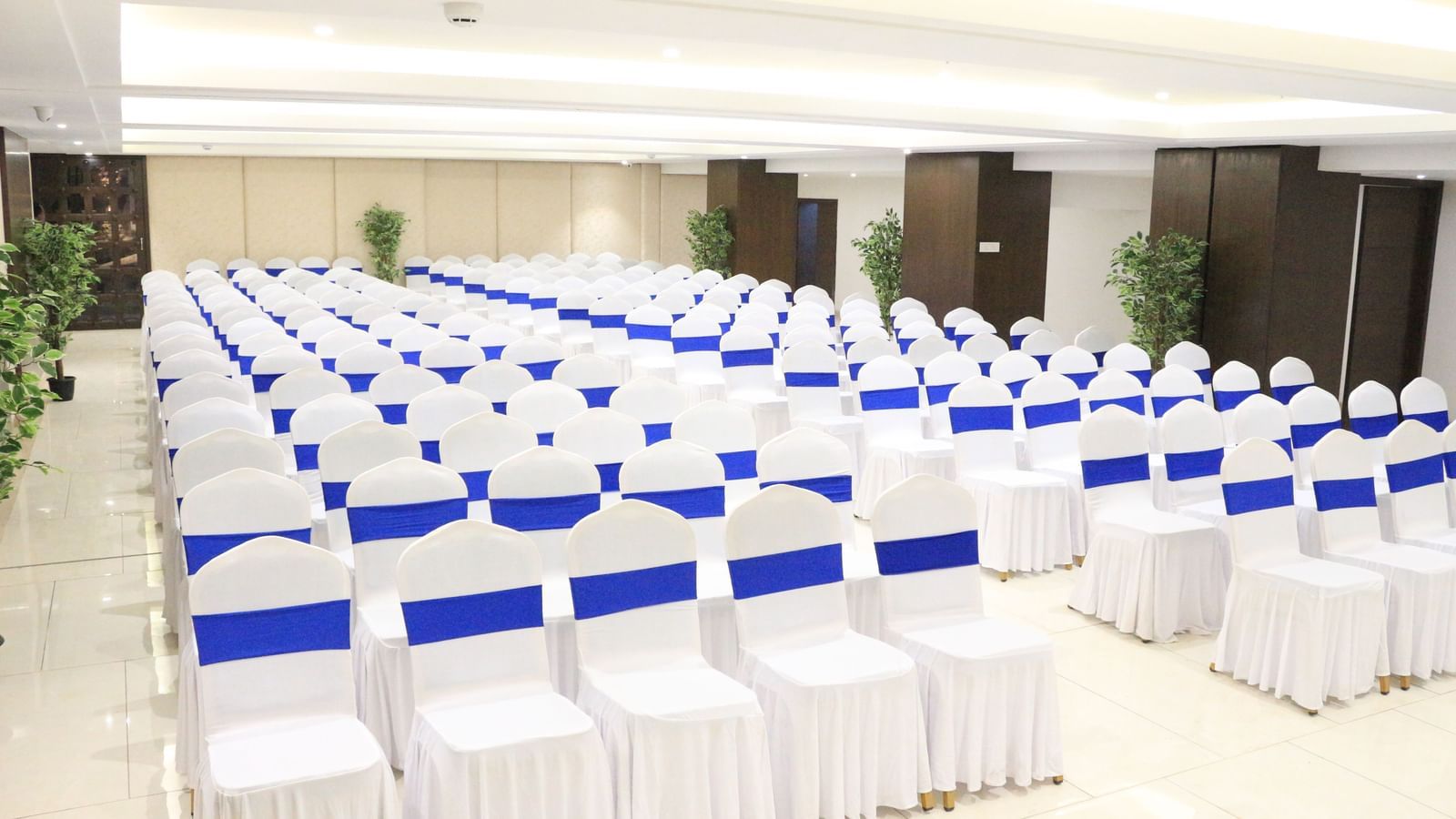 A banquet hall with neatly arranged chairs on both sides, creating a pathway in the middle at The Hamuse Hotel, Kodaikanal.