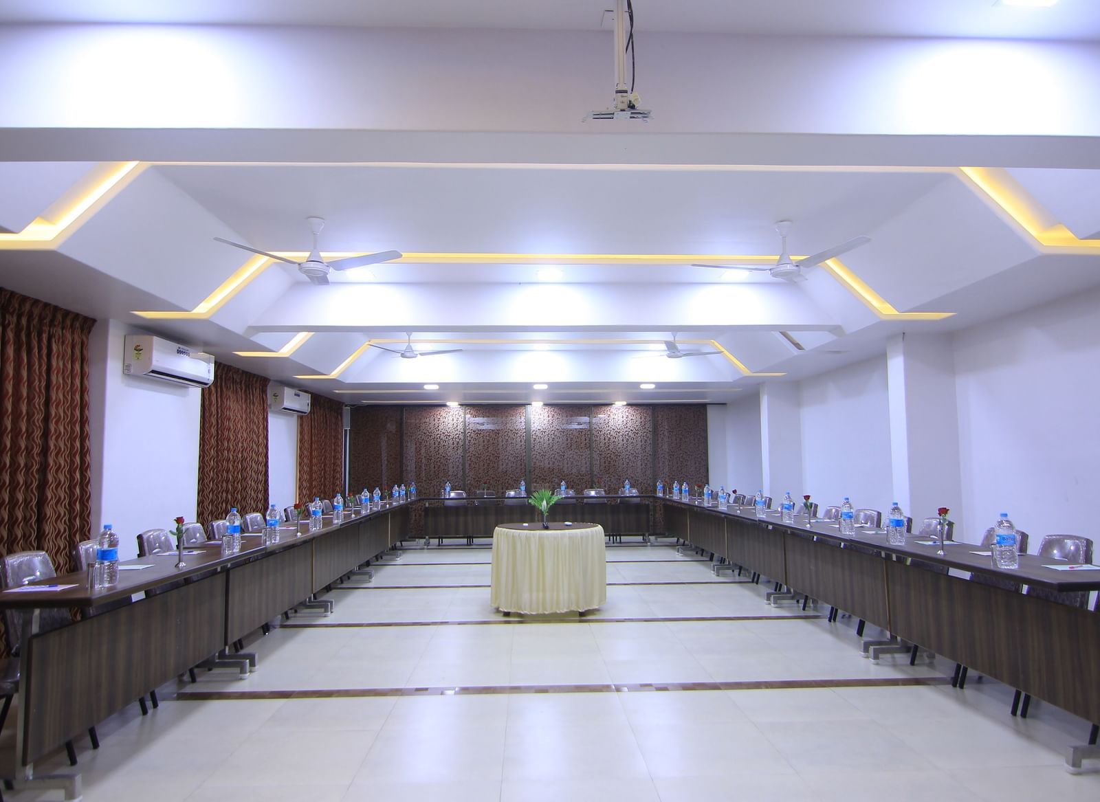 A well-lit conference room at Krushnai Resort with tables set up in a U-shaped arrangement.