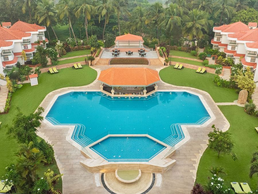 Aerial view of a large resort with a central swimming pool and landscaped gardens.
