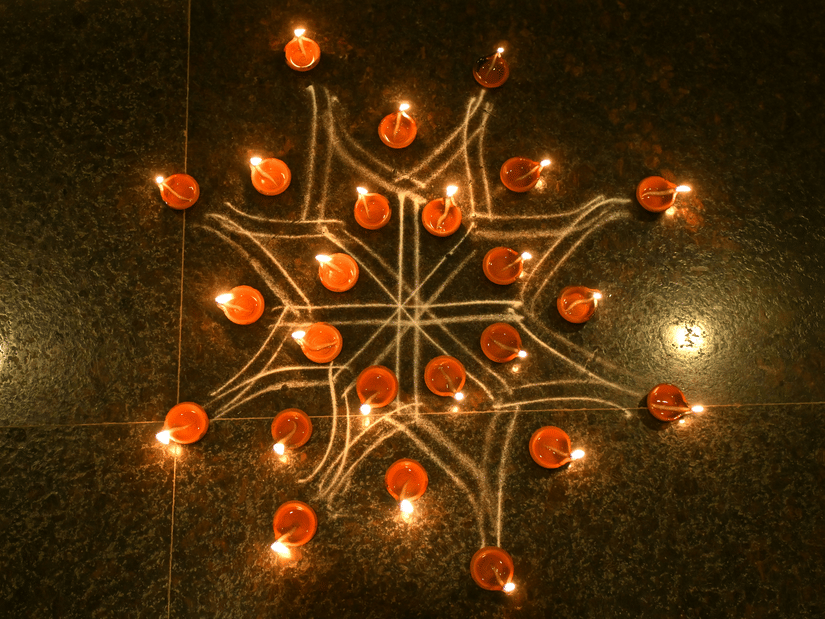 Traditional oil lamps for Karthigai Deepam arranged in a star-shaped pattern, glowing against a dark background