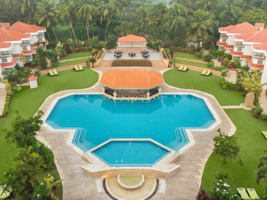 Aerial view of a large resort with a central swimming pool and landscaped gardens.