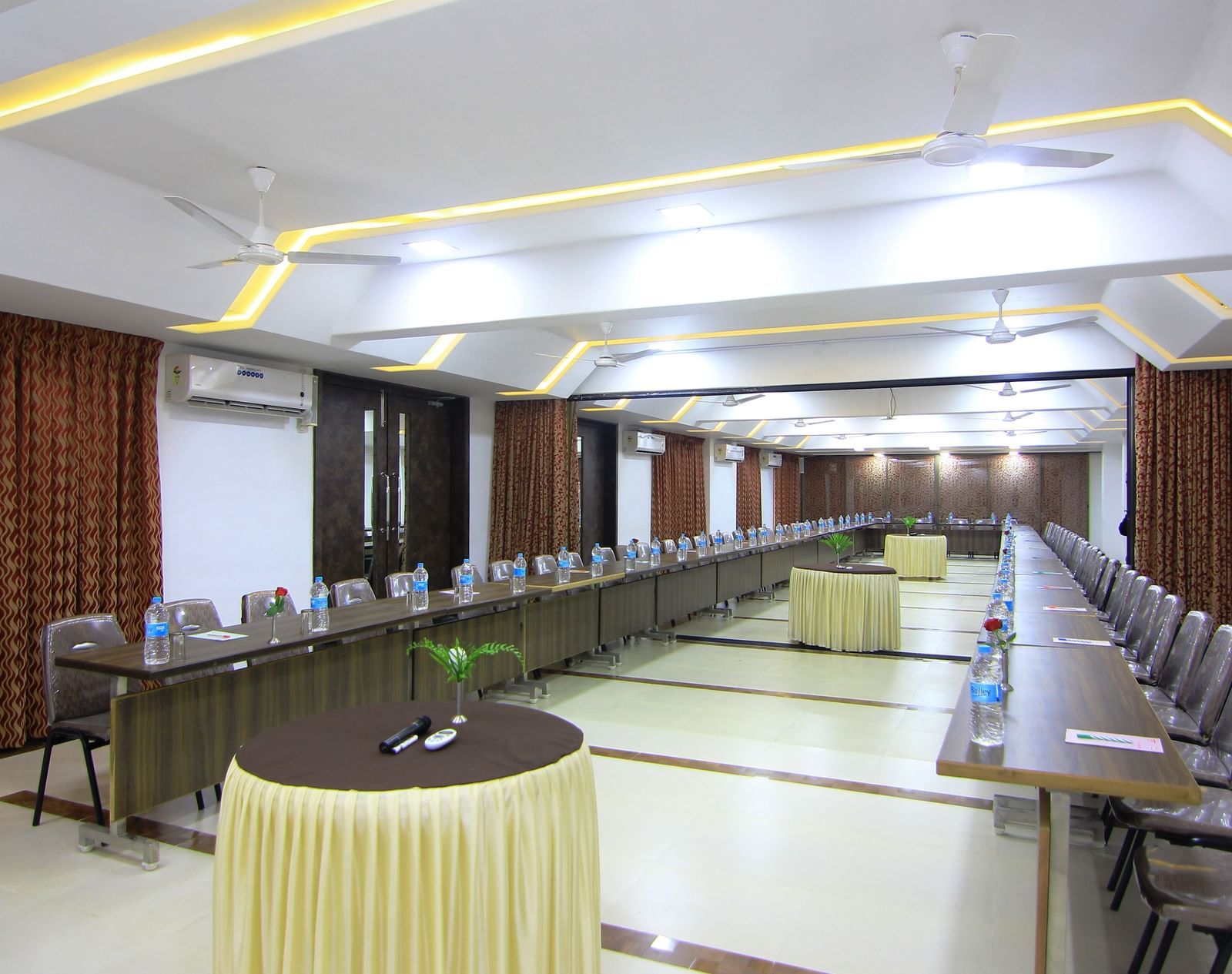 Wide view of a conference room at Krushnai Resort showing tables arranged in a U-shape with chairs on both sides, multiple round tables placed evenly at the centre.