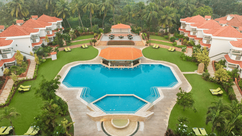 Aerial view of a large resort with a central swimming pool and landscaped gardens | South Goa Hotel near Beach