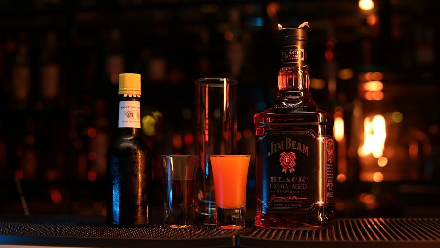 Premium bourbon and bitters with shot glasses on a bar counter at Sarovar Portico, Sonipat — showcasing the vibrant nightlife ambience.