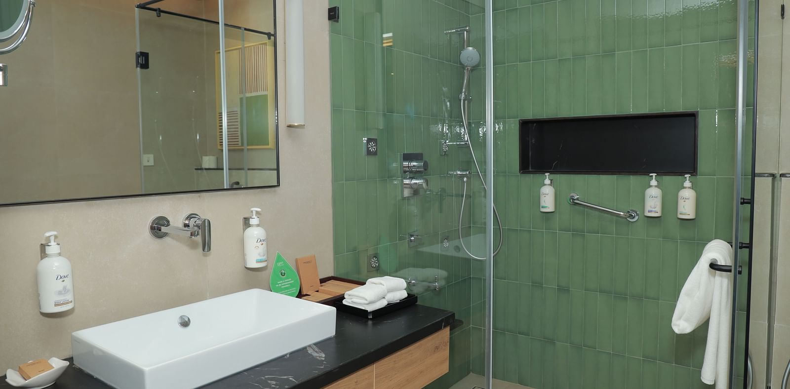 An image of a washroom in our suite in Tuticorin, featuring a large sink, a wall-mounted mirror, and a separate shower cubicle - Regency Tuticorin by GRT Hotels