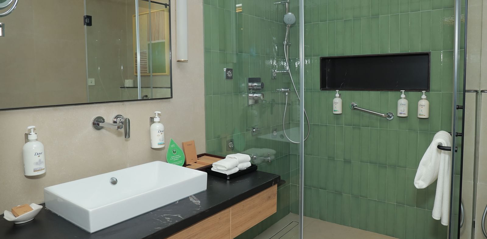 An image of a washroom in our suite in Tuticorin, featuring a large sink, a wall-mounted mirror, and a separate shower cubicle - Regency Tuticorin by GRT Hotels