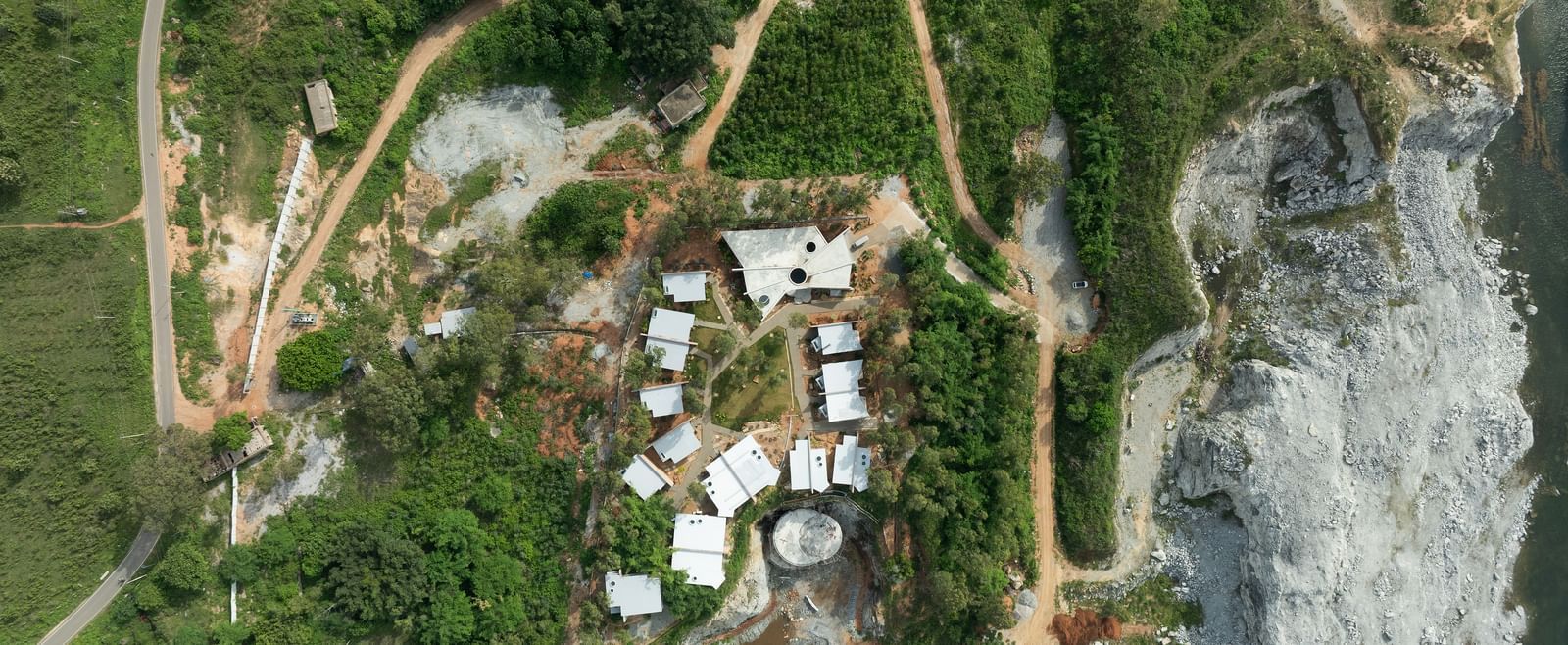 An aerial view of a cluster of buildings nestled within a natural, somewhat arid landscape | Gaia Studio | RD's Nature Retreat, Bangalore