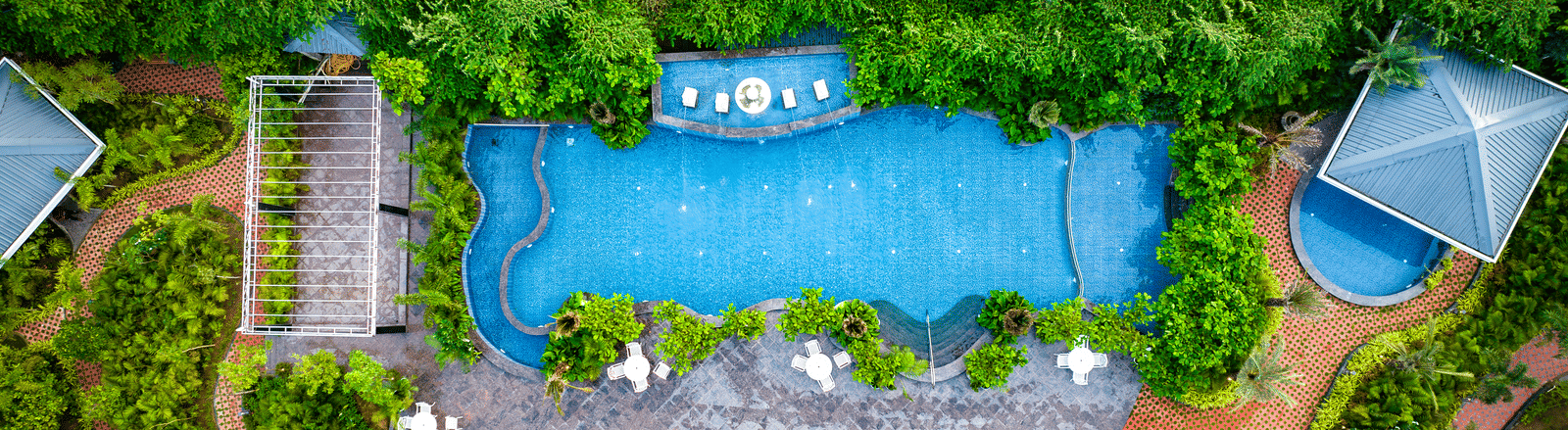Aerial view of swimming pool surrounded by lush gardens at MAYFAIR Oasis Resort and Convention Jharsuguda