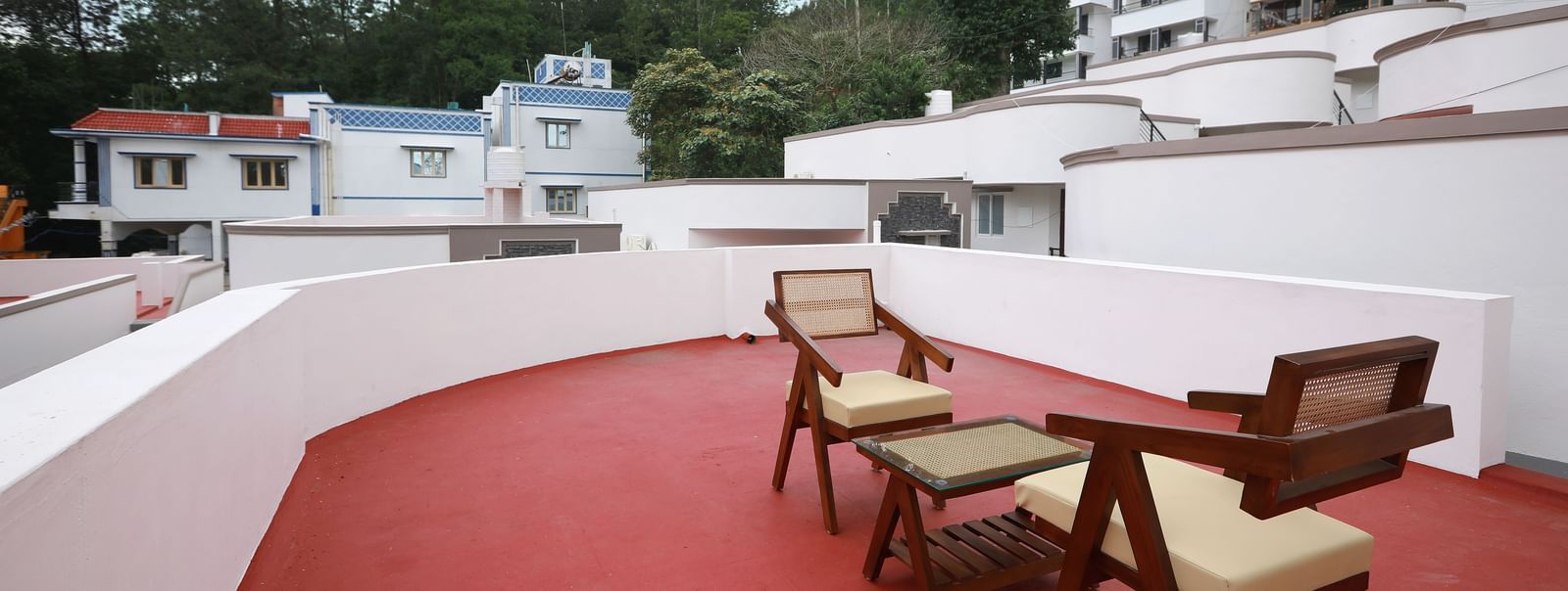 The terrace area at the Terrace Cottage with an outdoor seating area with a backdrop of lush green trees and a serene blue sky in the background at WOW Naturefull Resorts, Yercaud.