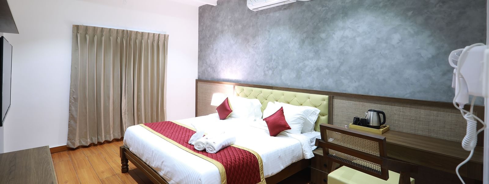 Full view of the Standard Room featuring a double bed beside a work desk with a chair along with a wall-mounted split AC at WOW Naturefull Resorts, Yercaud.