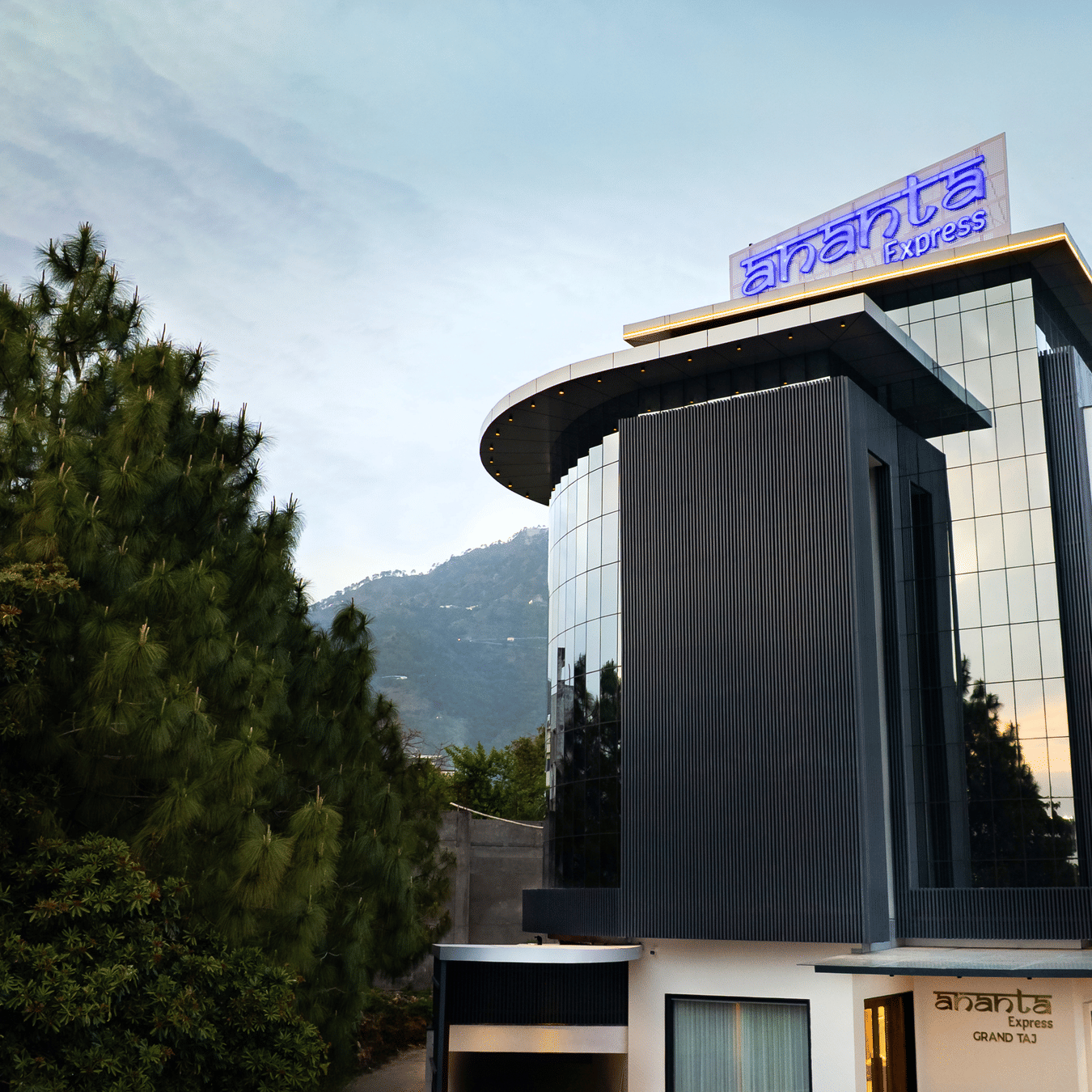 The modern multi-storey exterior of the hotel building with large glass windows during the day at Ananta Express, Katra.