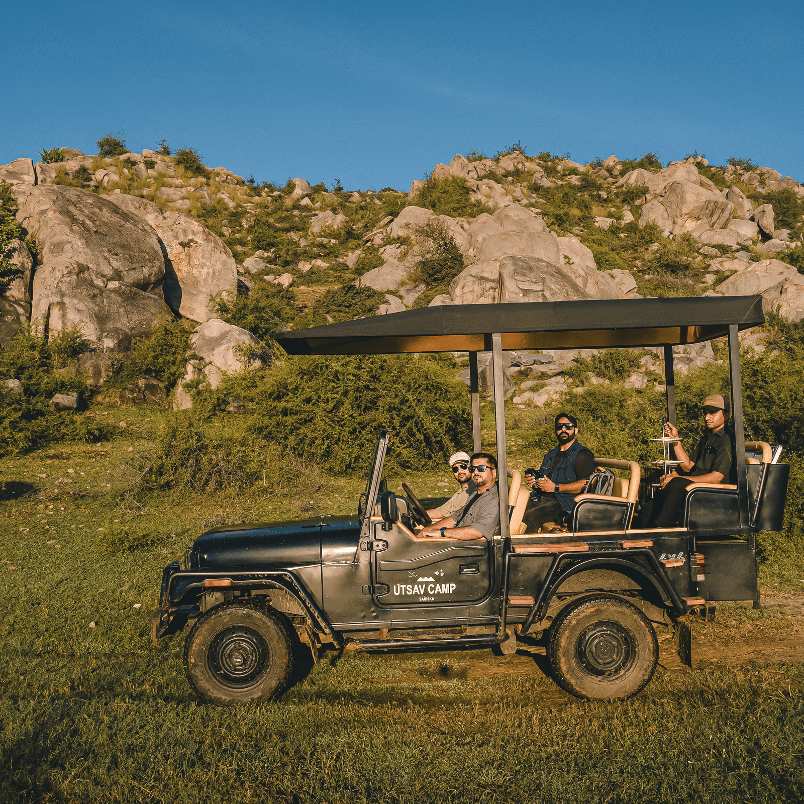 A group of people on a safari jeep with a hill in the background - Utsav Camp Sariska