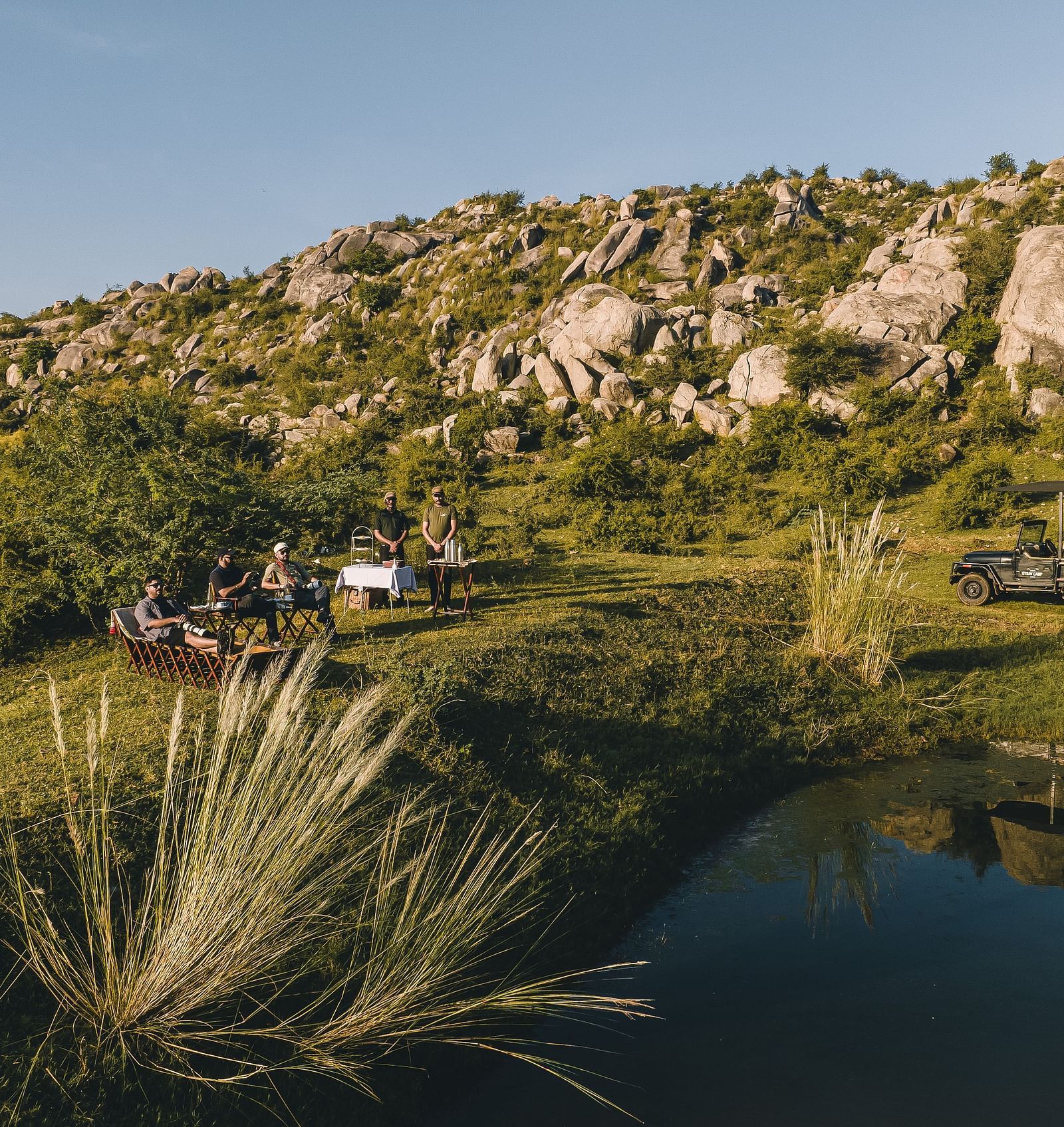 An image of a lake with the backdrop of a rocky mountain - Utsav Camp Sariska