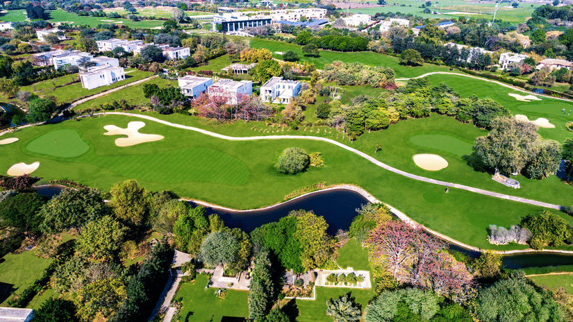 An aerial view of Karma Lakelands, Golf Course Near Delhi, with many building and golf course in view.