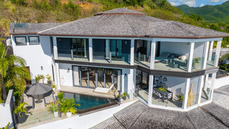 Elevated view of a modern ocean-facing villa with wraparound glass windows at Tamarind Hills Resort and Villas - Antigua.