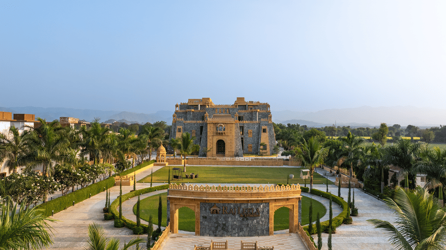 A symmetrical view of the circular lawn, paved paths, and the main building of EsthereaRaj Leela, Ranakpur.