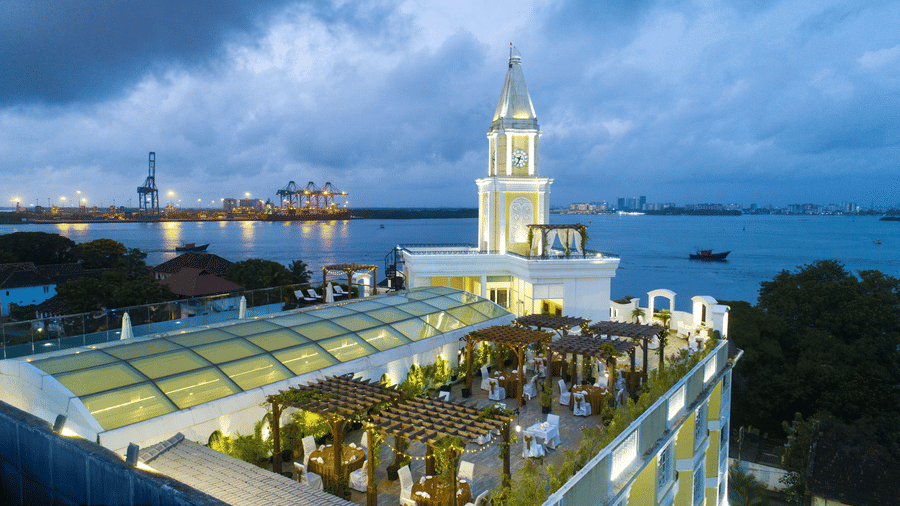 Aerial view of the hotel with the sky and beach in the background, surrounded by trees