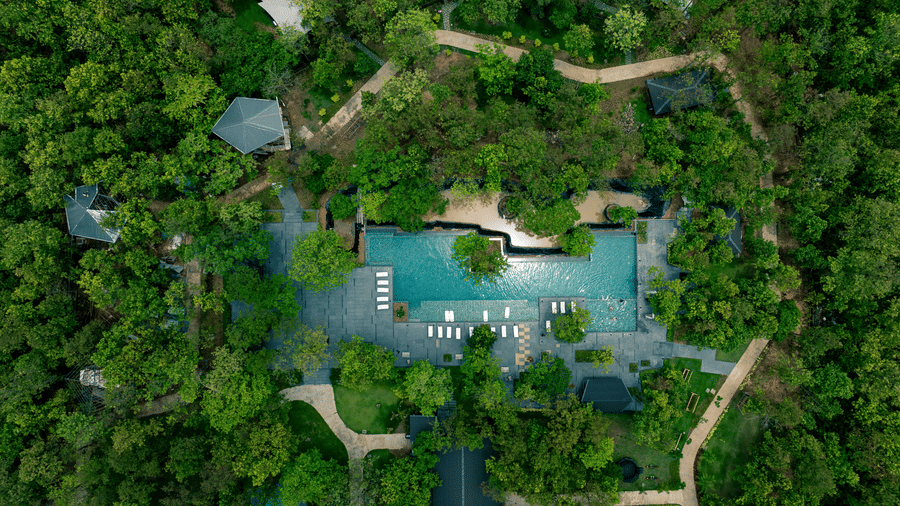Aerial view of Hotel Sonar Bangla Joypur Forest, Bankura, showcasing its pool nestled amid lush, dense woodland surroundings.