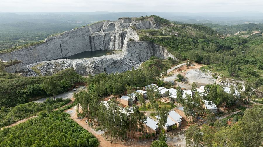 An expansive aerial view showing a large quarry or excavation site with scattered buildings and vegetation | Gaia Studio | RD's Nature Retreat, Bangalore