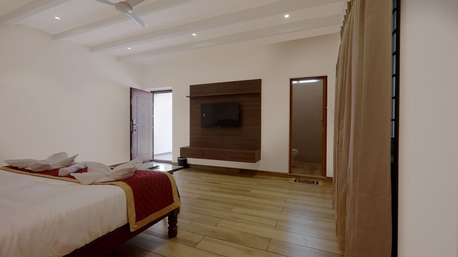 Corner view of the Terrace Cottage featuring a wall-mounted television placed opposite to the double bed at WOW Naturefull Resorts, Yercaud.