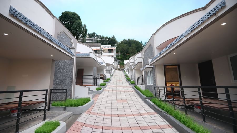 A bright exterior shot of the pathway going upwards at WOW Naturefull Resorts, Yercaud, with cottages on either side of the pathway.