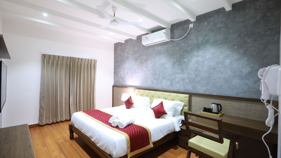 Full view of the Standard Room featuring a double bed beside a work desk with a chair along with a wall-mounted split AC at WOW Naturefull Resorts, Yercaud.