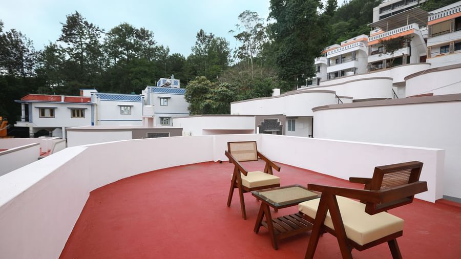 The terrace area at the Terrace Cottage with an outdoor seating area with a backdrop of lush green trees and a serene blue sky in the background at WOW Naturefull Resorts, Yercaud.