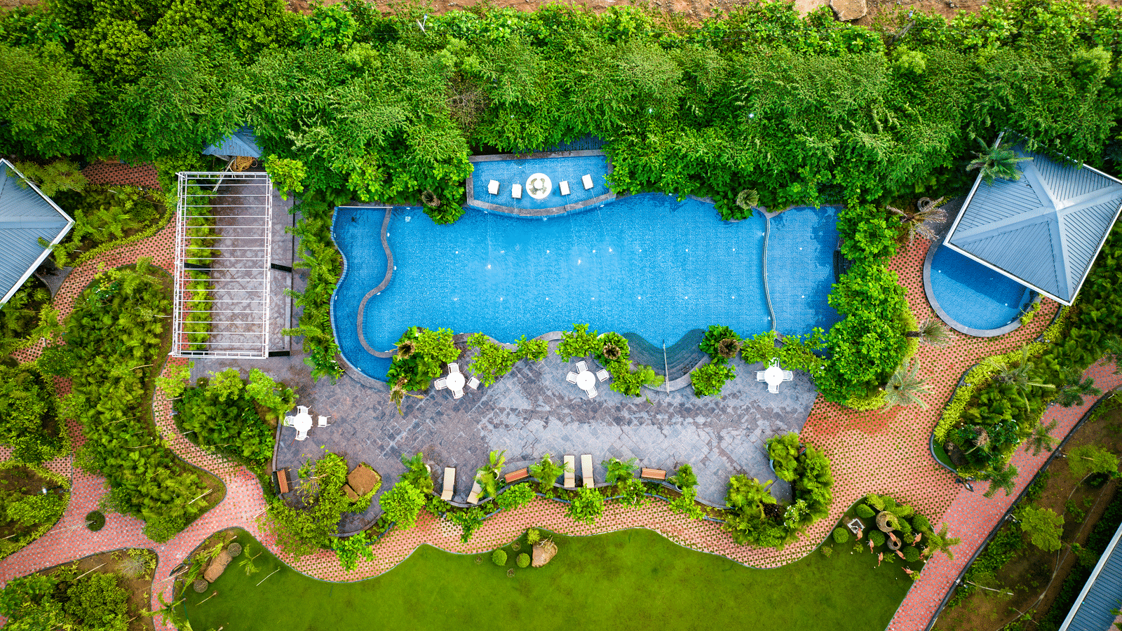 Aerial view of swimming pool surrounded by lush gardens at MAYFAIR Oasis Resort and Convention Jharsuguda