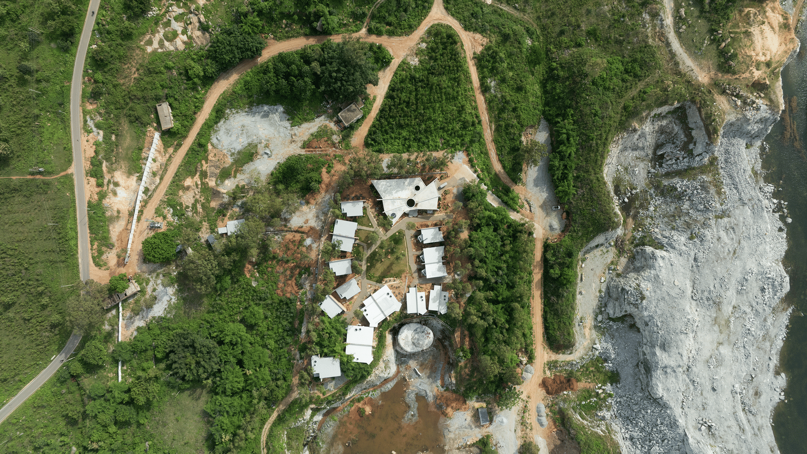 An aerial view of a cluster of buildings nestled within a natural, somewhat arid landscape | Gaia Studio | RD's Nature Retreat, Bangalore